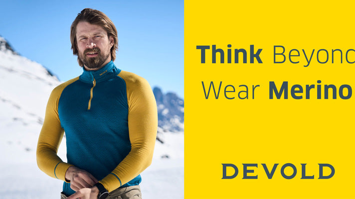 Auf dem Bild ist ein Mann zu sehen, der eine Longsleeve von DEVOLD in blau/gelb trägt.