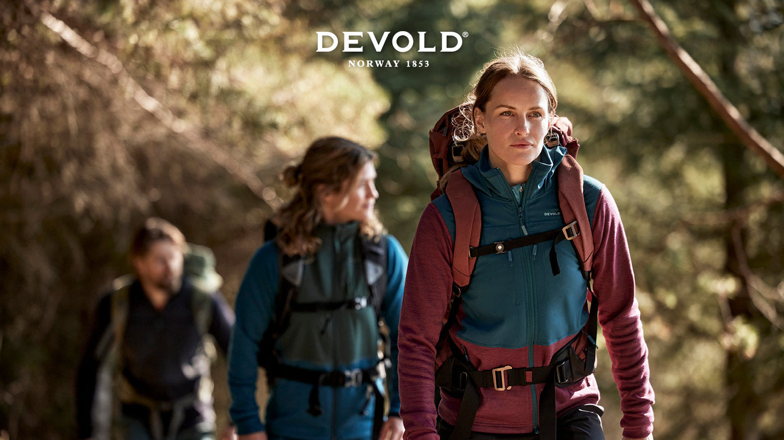 Devold Marketing Kampagne: 3 Personen laufen mit Wanderausrüstung durch den Wald.