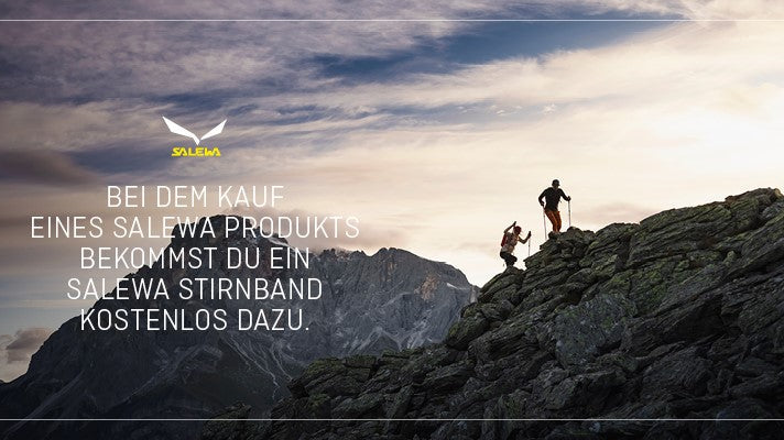 Auf dem Bild sieht man 2 Personen die auf einen Felsen steigen. Im Horizont sieht man einen Berg im Hintergrund.