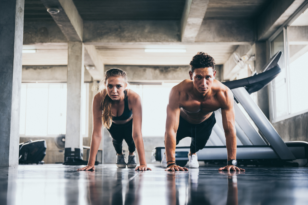 Eine Frau und ein Mann machen Liegestütze in einem Fitnessstudio.