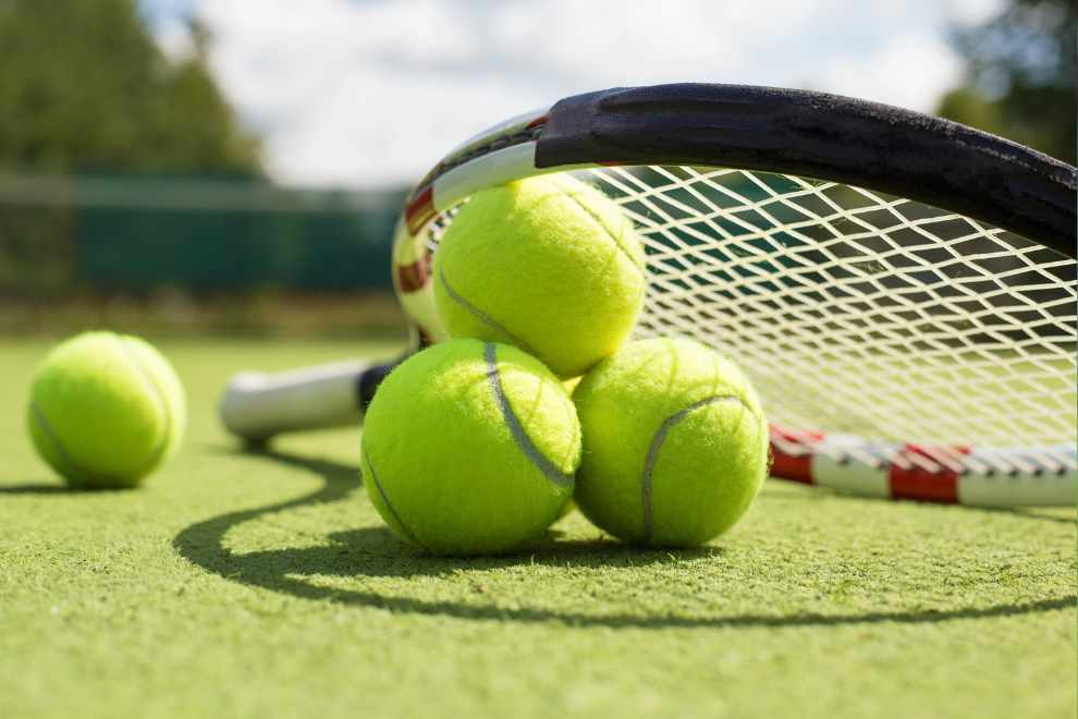 3 Tennisbälle liegen aufeinander gestapelt im Bild. Darauf angelehnt ist ein Tennisschläger.