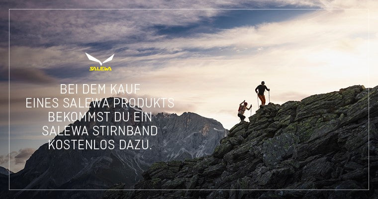 Auf dem Bild sieht man 2 Personen die auf einen Felsen steigen. Im Horizont sieht man einen Berg im Hintergrund.