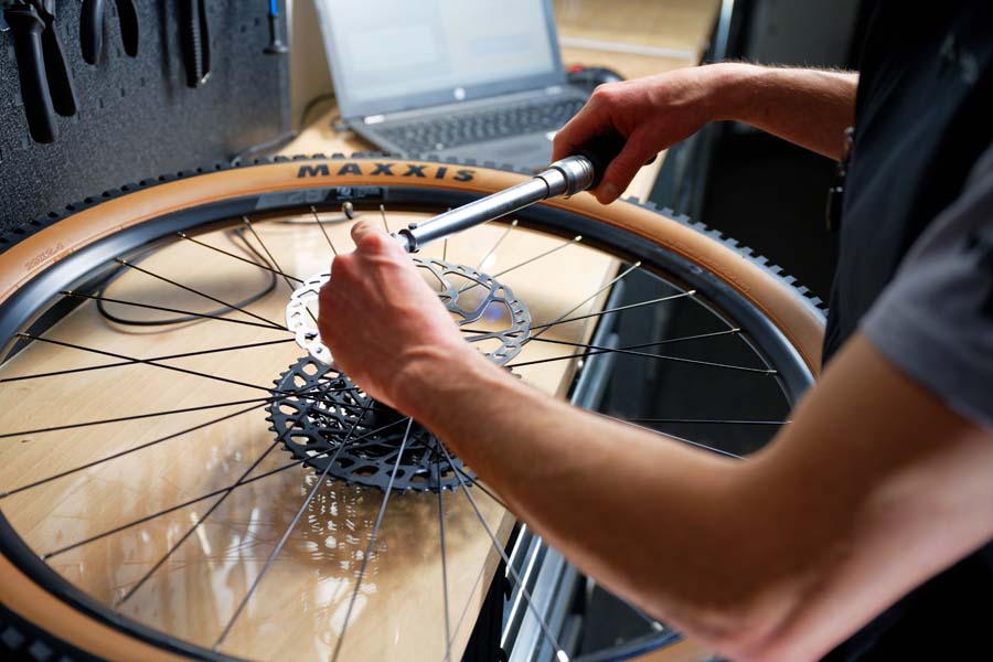 Fahrradmechaniker arbeitet an einem Laufrad und schraubt an der Scheibenbremse